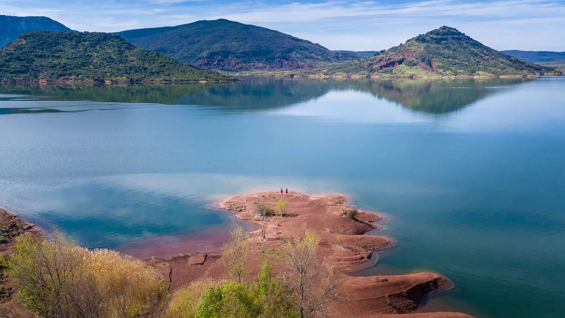 Deux randonneurs contemplent le lac du Salagou depuis la rive des Vailhés