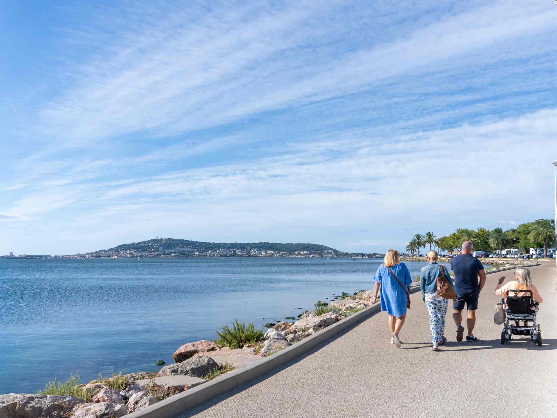 Groupe d'amis dont une personne en fauteuil roulant qui se balade sur la promenade Spirosi à Balaruc-les-Bains