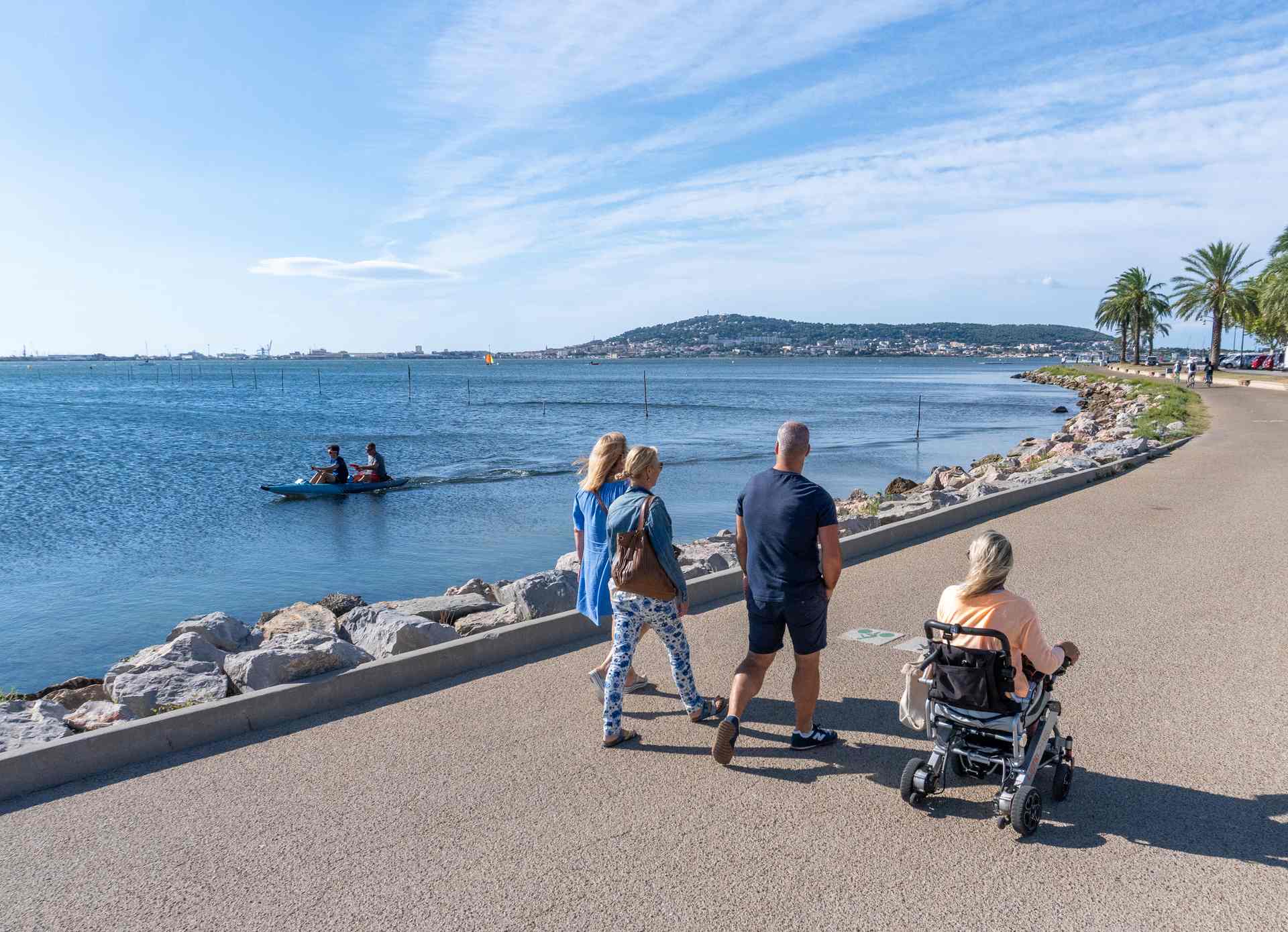 Groupe d'amis dont une personne en fauteuil roulant qui se balade sur la promenade Spirosi à Balaruc-les-Bains