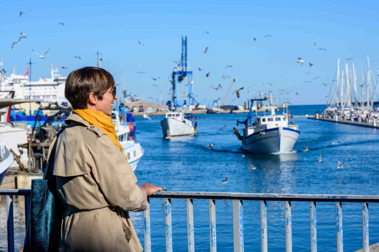 Jeune femme qui regarde un Chalutier qui rentre dans le port de Sète